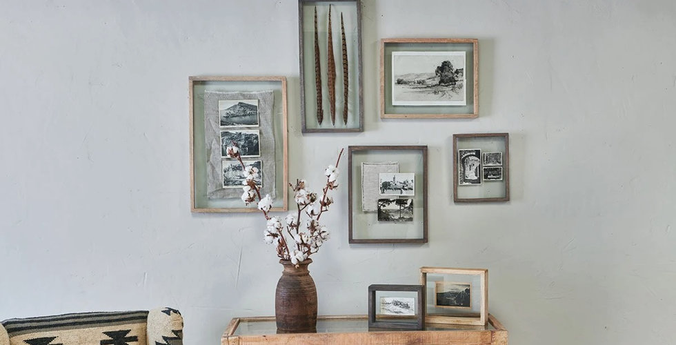 A gallery wall of photographs and framed objects such a pressed flowers and feathers.