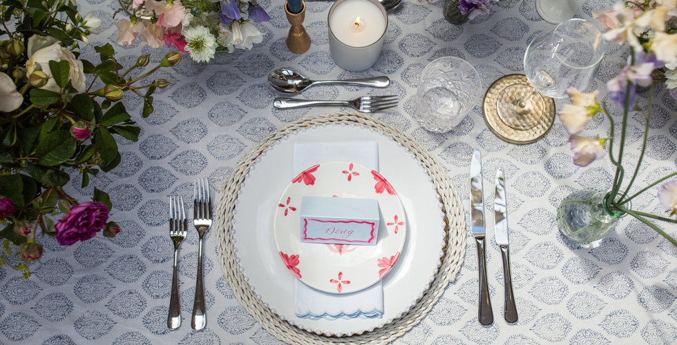 An aerial shot of a place setting, with a block printed tablecloth, silver cutlery and a printed dinner plate. 