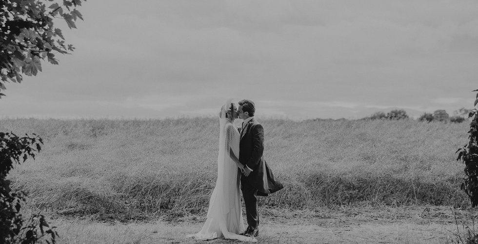 The bride and groom share a kiss in the field.