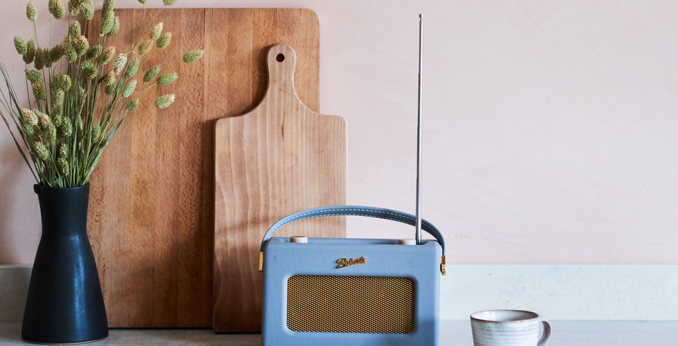 A kitchen counter with a Roberts Radio, a coffee cup, a wooden chopping board.