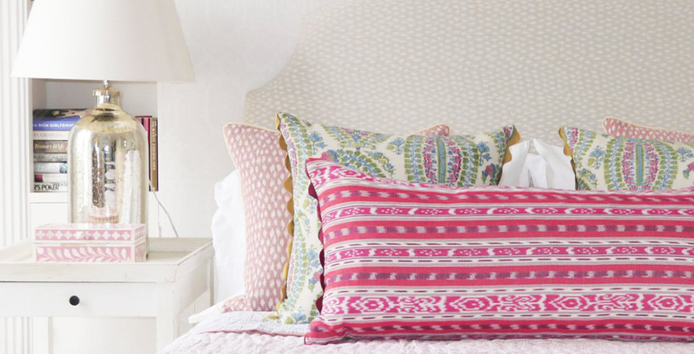 A bed styled with green and pink scatter cushions.